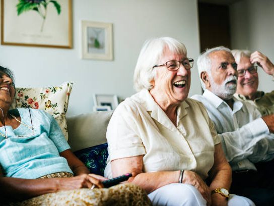 Senior people watching television together